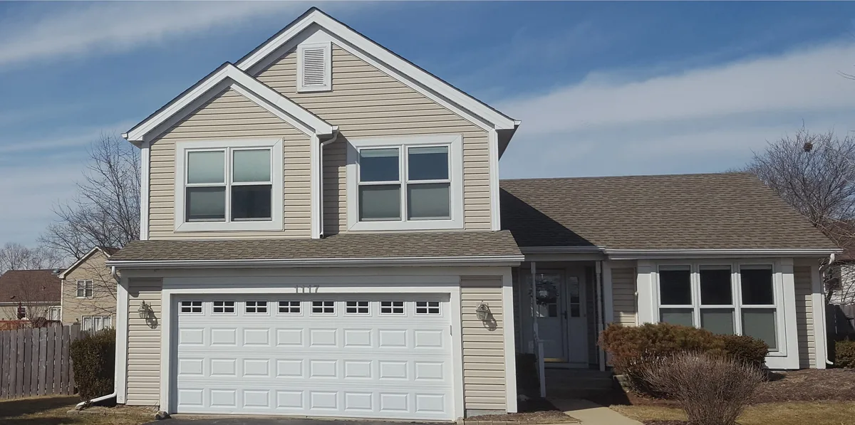 Finished two-story suburban home with new siding, trim and gutters under a blue sky