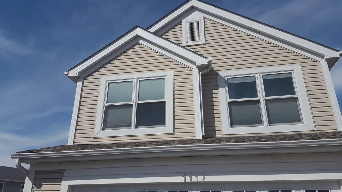 Close view of new white gutters and fascia along the roofline of a two-story home